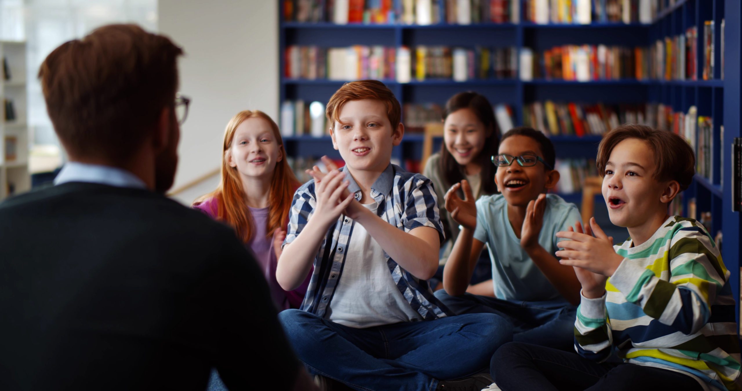 Multiethnic,Group,Of,Kids,Sitting,On,Floor,Near,Teacher,And